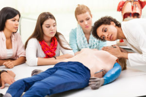 Instructor demonstrates CPR to medical students Female instructor demonstrating chest compressions on a CPR dummy.